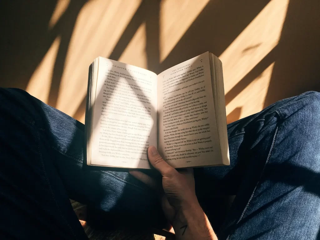person-holding-book-sitting-on-brown-surface